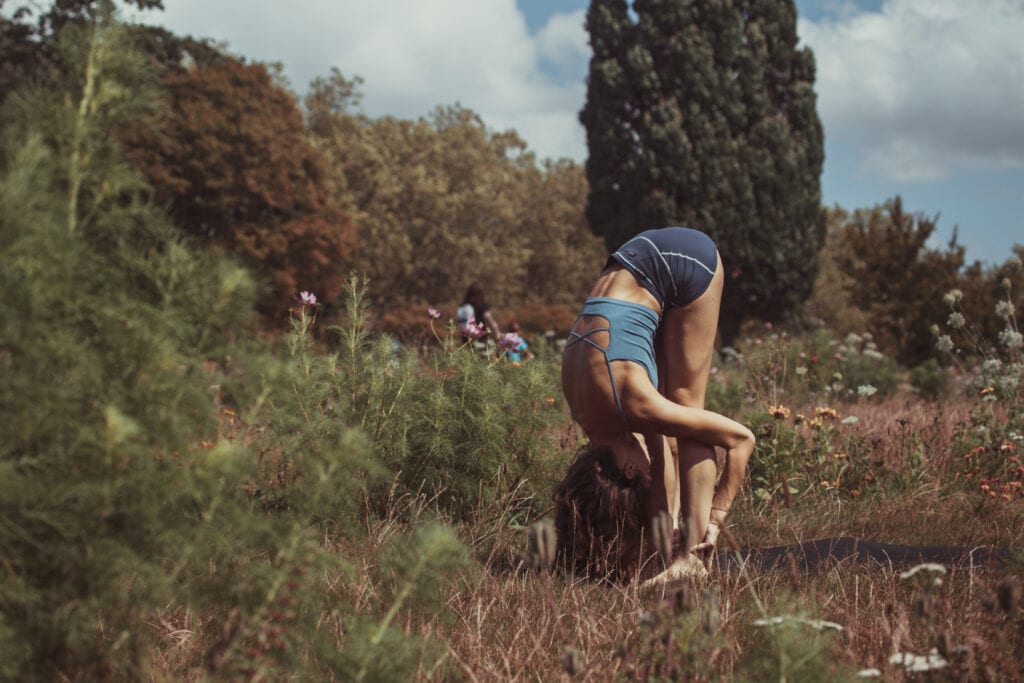 A woman doing a handstand in the grass.