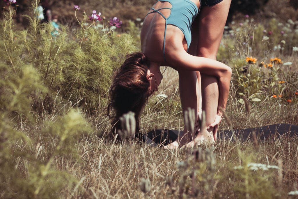 A woman bending over in the grass with her head down.