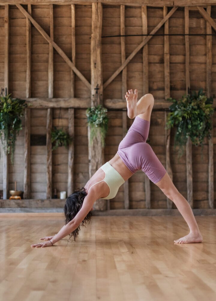 A woman in the downward dog pose on a wooden floor.