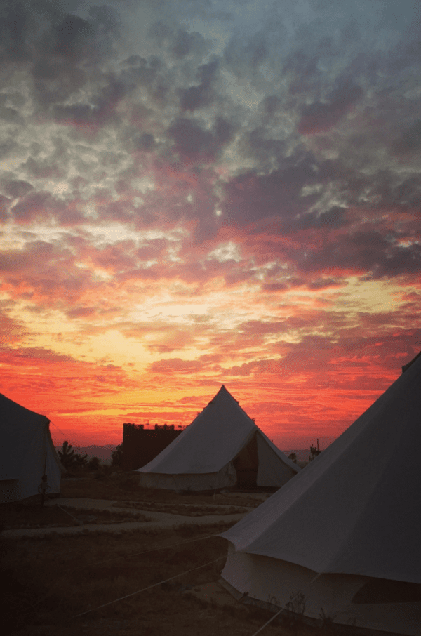 A sunset with some tents in the background