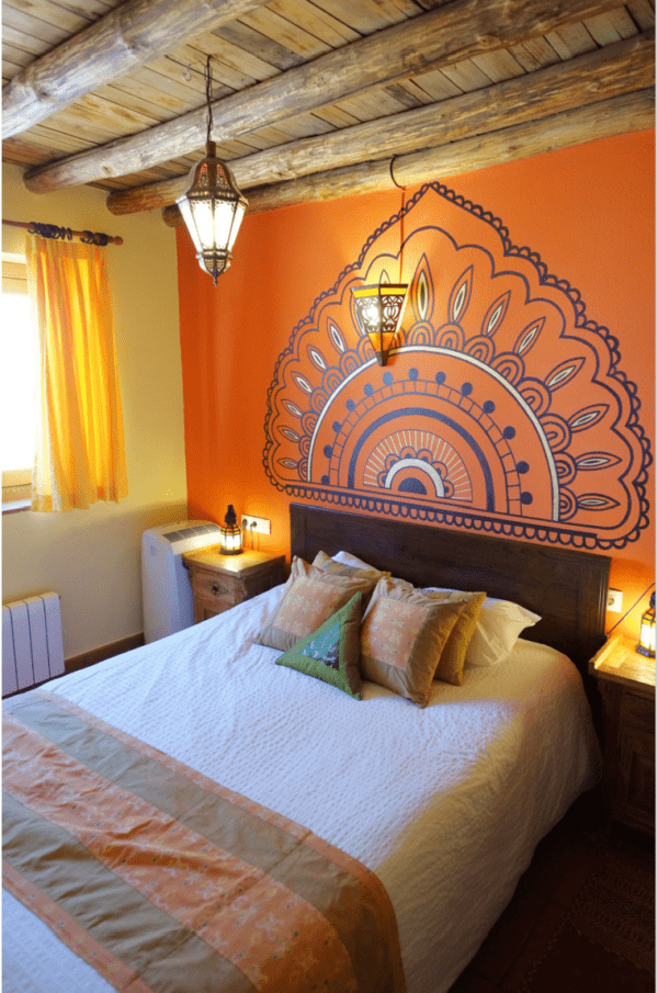 A bedroom with an orange wall and a large headboard.