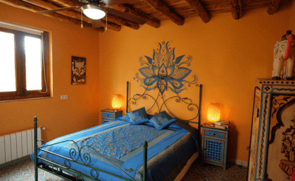 A bed room with a blue bedspread and two lamps