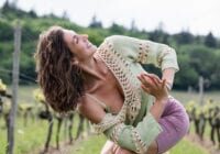 A woman in a field with trees behind her.