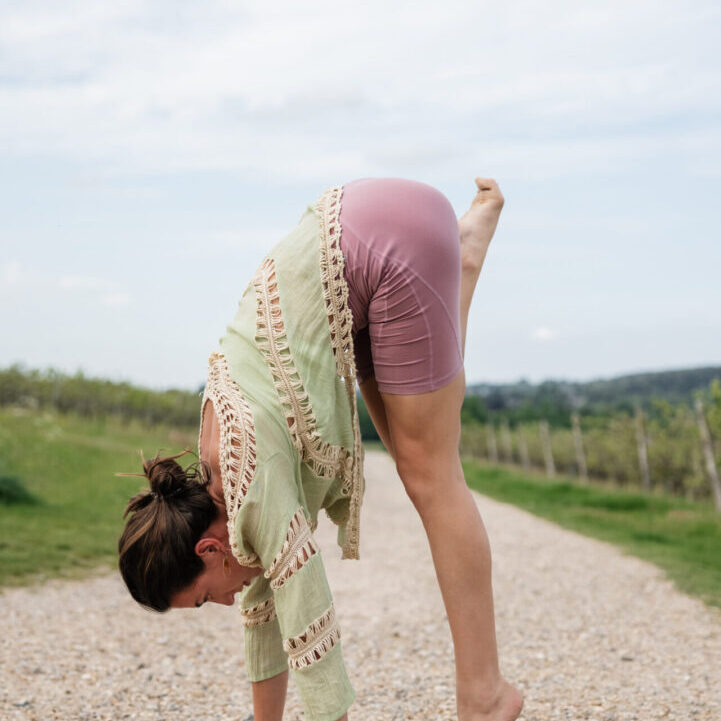 A woman doing a handstand on the side of a road.